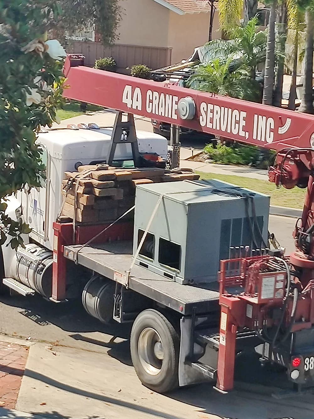 Crane truck delivering a commercial HVAC unit to a rooftop installation